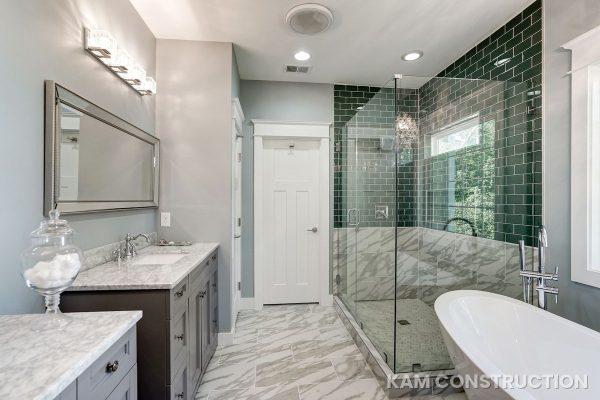 Primary bathroom with green subway tile shower and freestanding tub